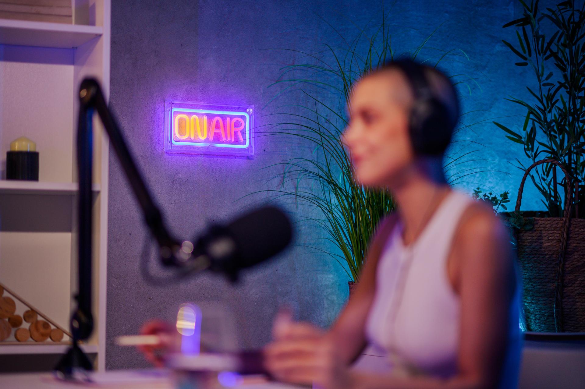 Selective focus on the neon "on air" sign in a home podcast recording studio.